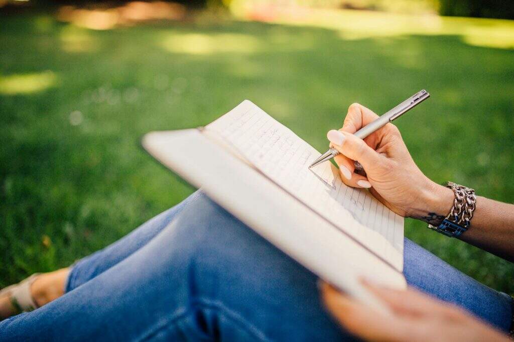 mulher sentada escrevendo em um caderno